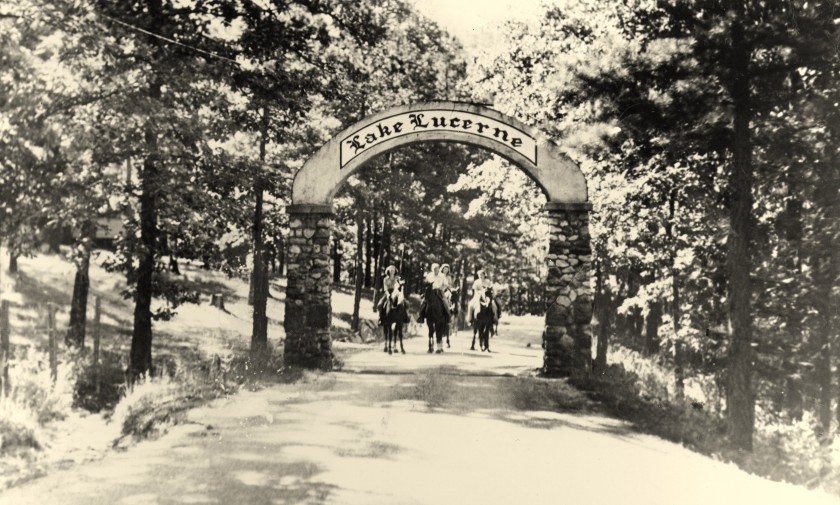 Entrance to Lake Lucerne with horseback riders under arch sign.